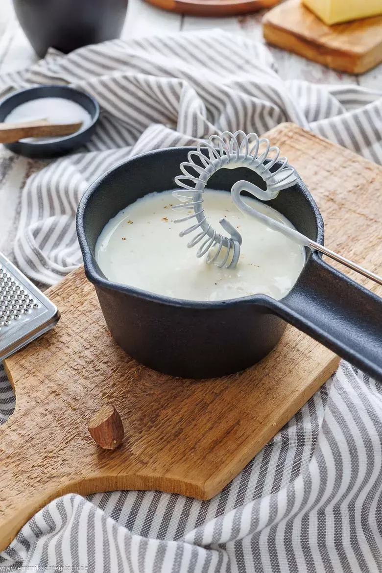 Selbstgemachte Béchamelsauce wird in einem Topf zu einer glatten Konsistenz gerührt