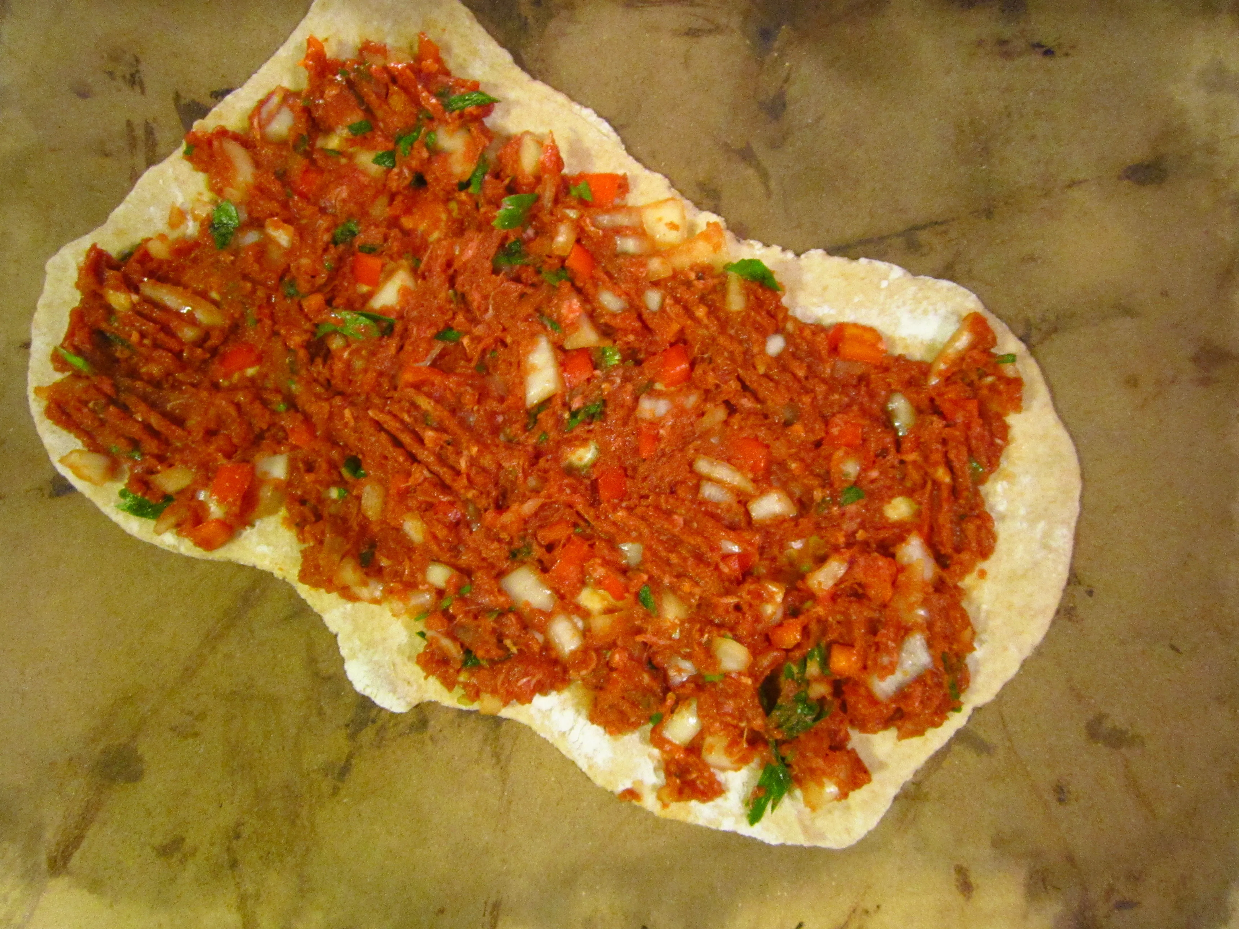 Selbstgemachte türkische Pizza auf einem Pizzastein, bereit für den Ofen, um eine knusprige Kruste zu erhalten.