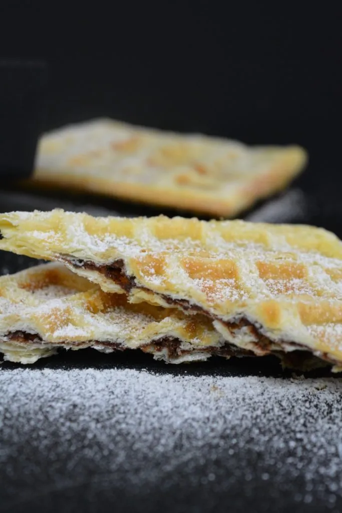Servierfertige Blätterteig-Nutella-Waffeln auf einem Teller, liebevoll mit Puderzucker bestäubt