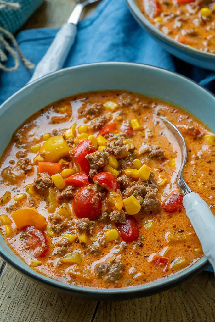 Servierfertige Pizzasuppe, appetitlich angerichtet, mit frischen Kräutern und geschmolzenem Käse.