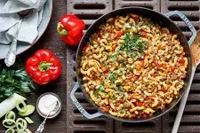 Servierfertige schnelle Hackpfanne mit Hörnchennudeln, garniert mit frischer Petersilie und einem Klecks Crème Fraîche.