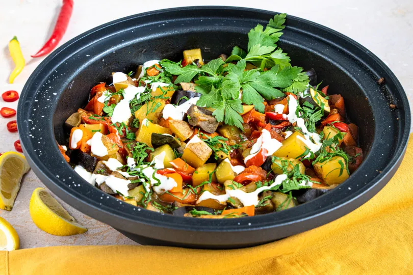 Servierfertige vegetarische Tajine mit frischen Kräutern und Beilagen