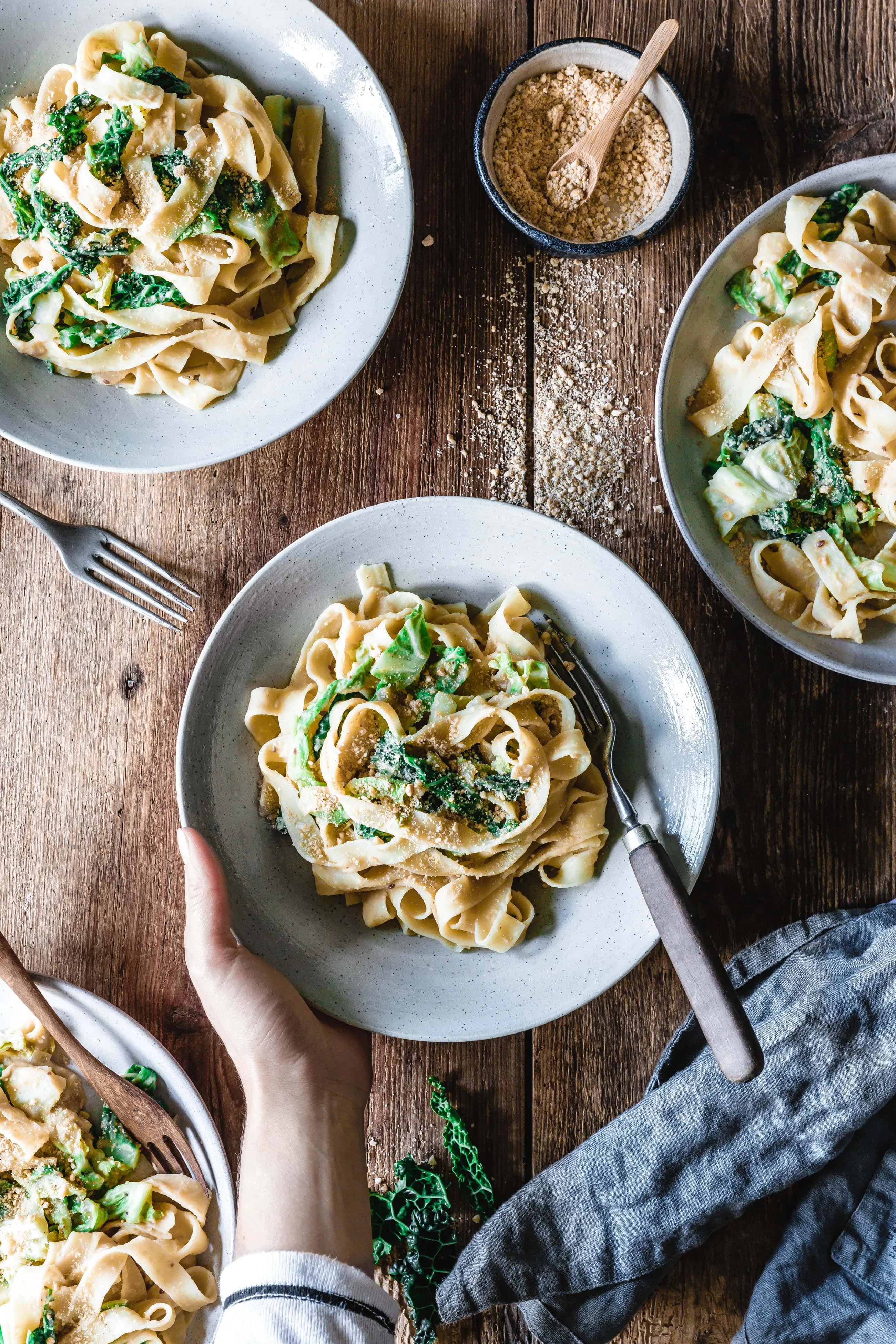 Servierte vegane Tagliatelle mit Wirsing und cremiger Hummussauce, garniert mit frischen Kräutern, bereit zum Genuss