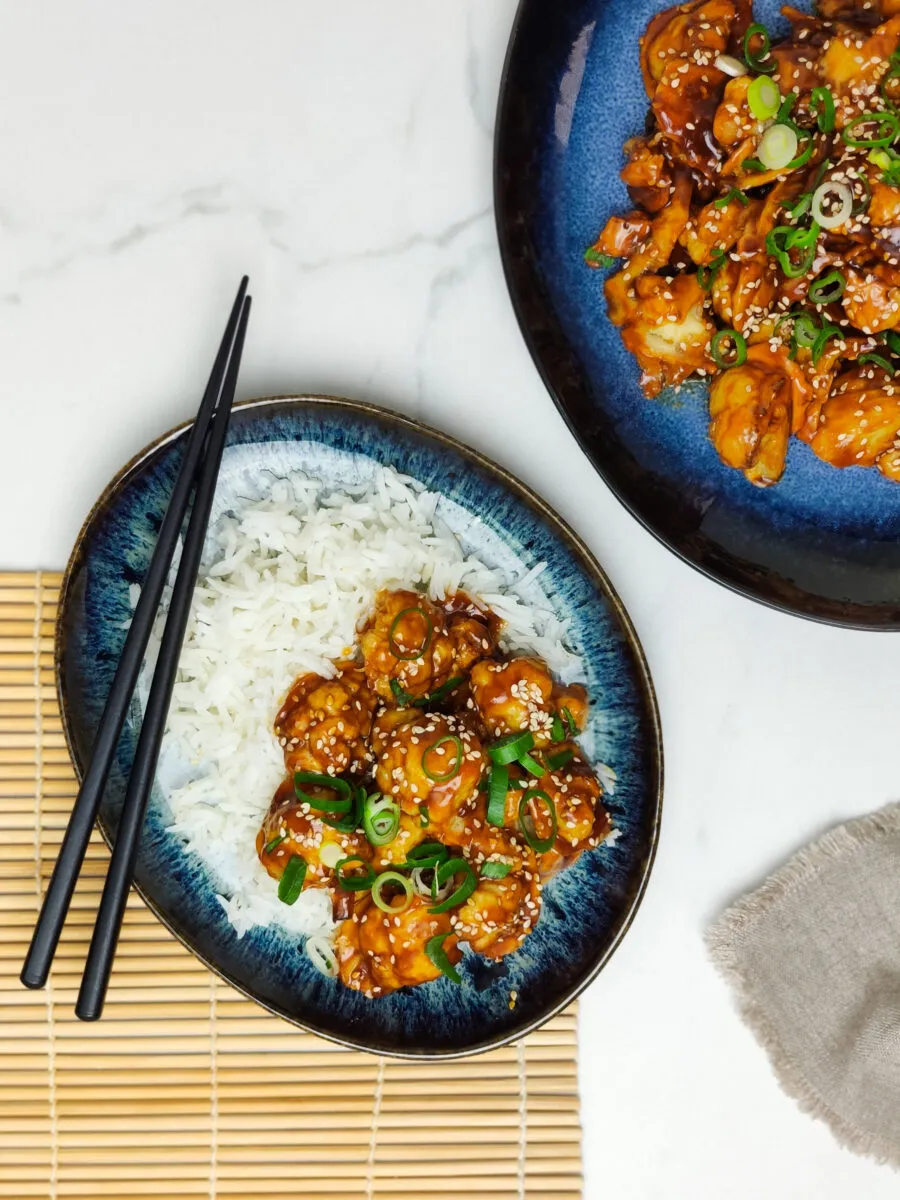 Servierter knuspriger Karfiol süß-sauer mit Reis und Frühlingszwiebeln