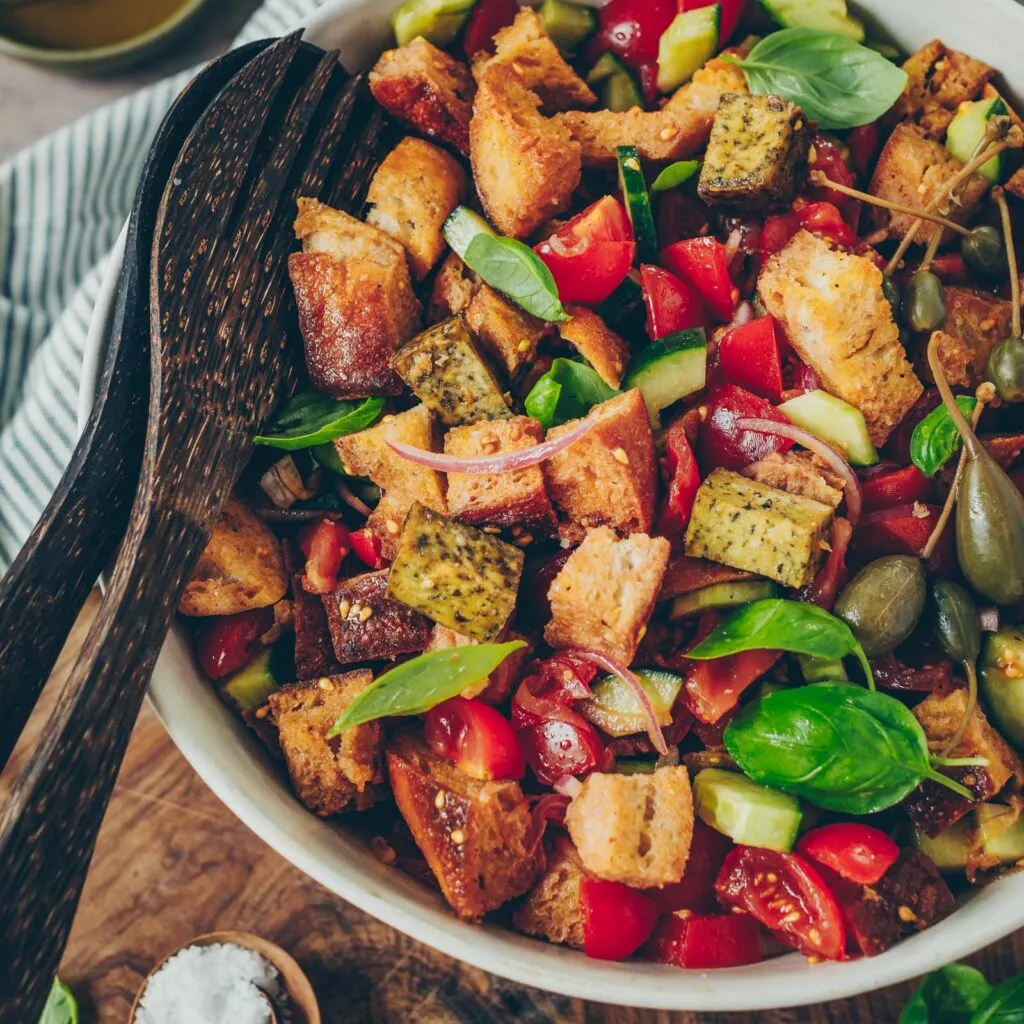 Servierter Panzanella mit Tofu, garniert mit frischem Basilikum und Oliven
