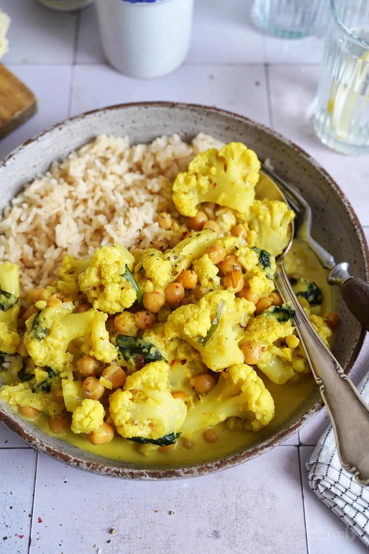 Serviertes veganes Kichererbsen Curry mit Beilagen wie Reis und Naan Brot