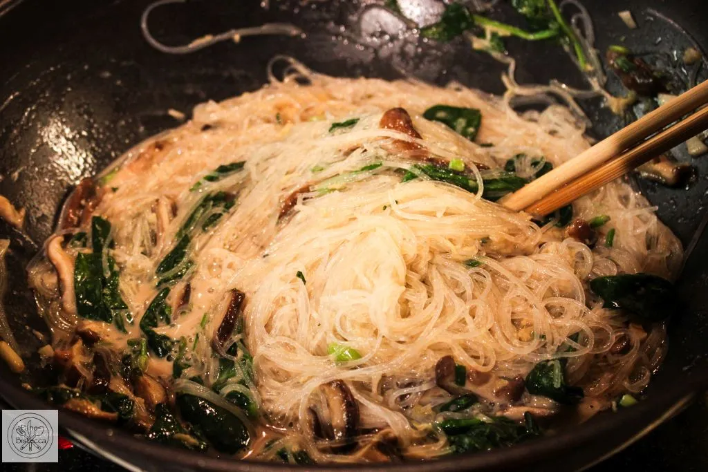 Shiitake Pilze und Knoblauch werden im Wok für die asiatischen Spinat Nudeln angebraten