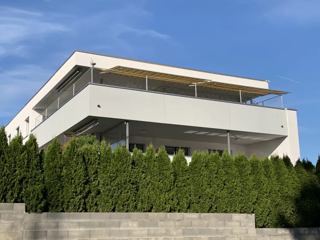 Sicheres Katzenschutznetz an einer Terrasse, die von Grün umgeben ist