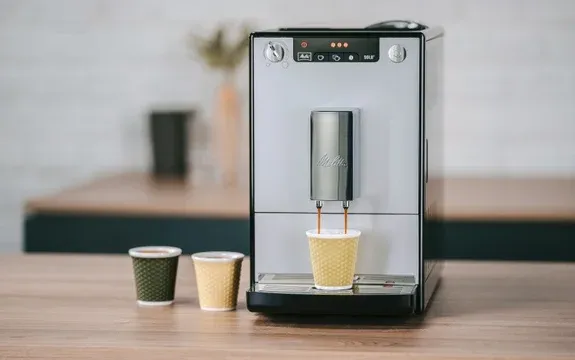 Silberner Melitta Purista Kaffeevollautomat füllt Kaffee in einen gelben To-Go-Becher