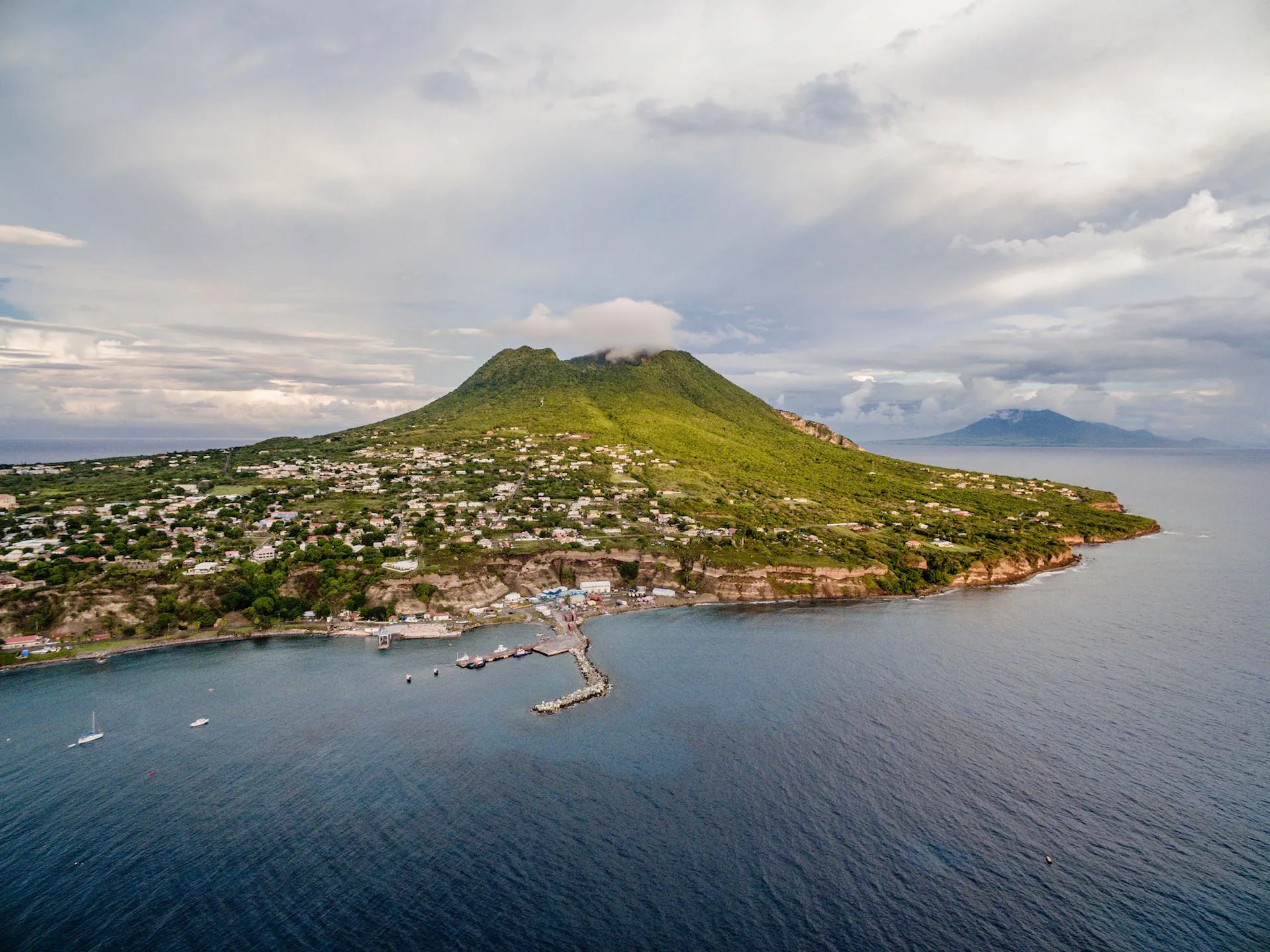 Sint Eustatius in der Karibik mit einem Vulkan im Hintergrund und einem bunten Küstenort