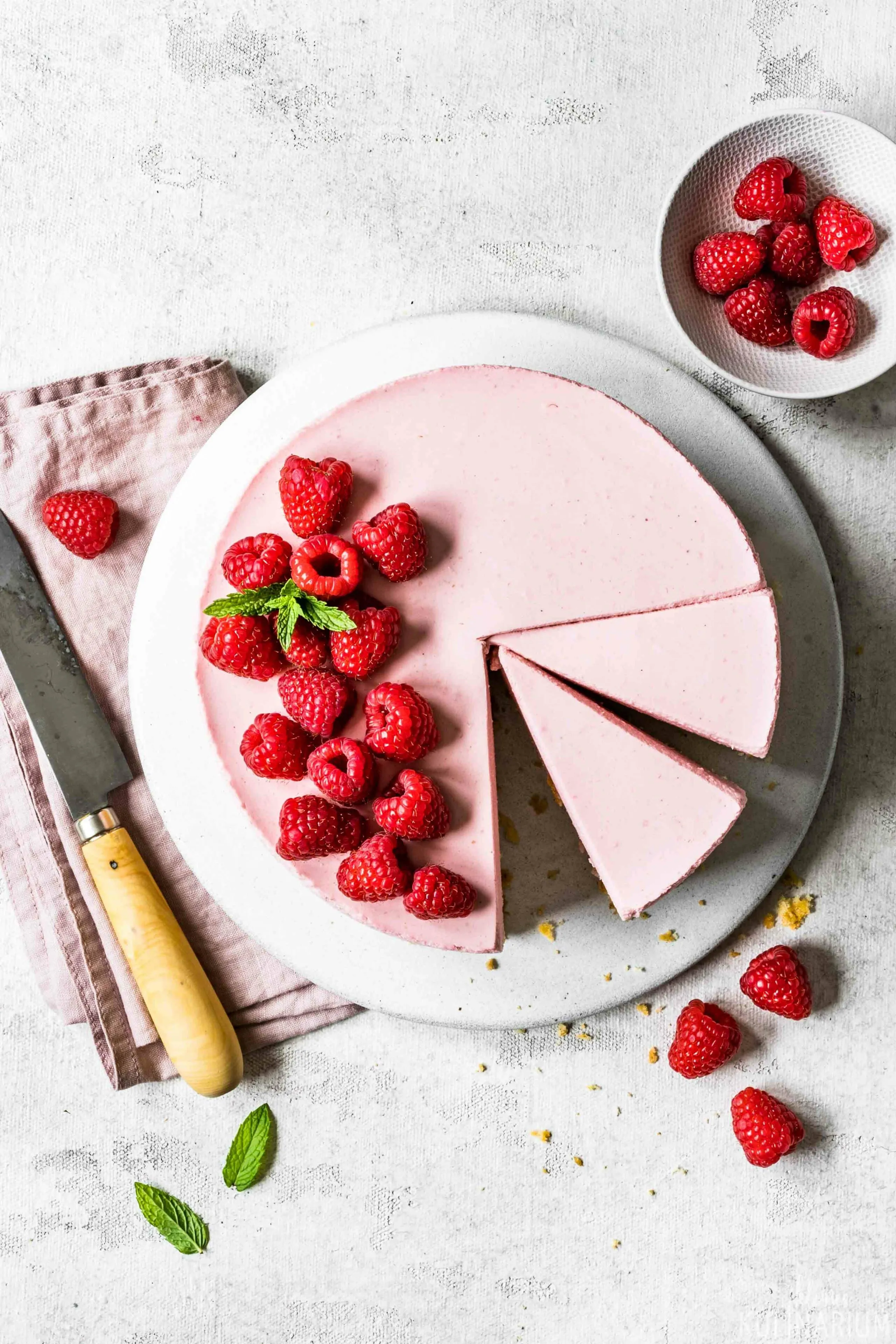 Sommerliche Himbeer-Sahne-Torte mit frischen Beeren und Minze, präsentiert auf einer Kuchenplatte – eine klassische Frucht Sahne Torte für die deutsche Kaffeetafel.