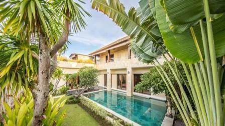 Sonniger Poolbereich eines Resorts in Canggu auf der indonesischen Insel Bali, umgeben von Palmen und tropischer Vegetation.