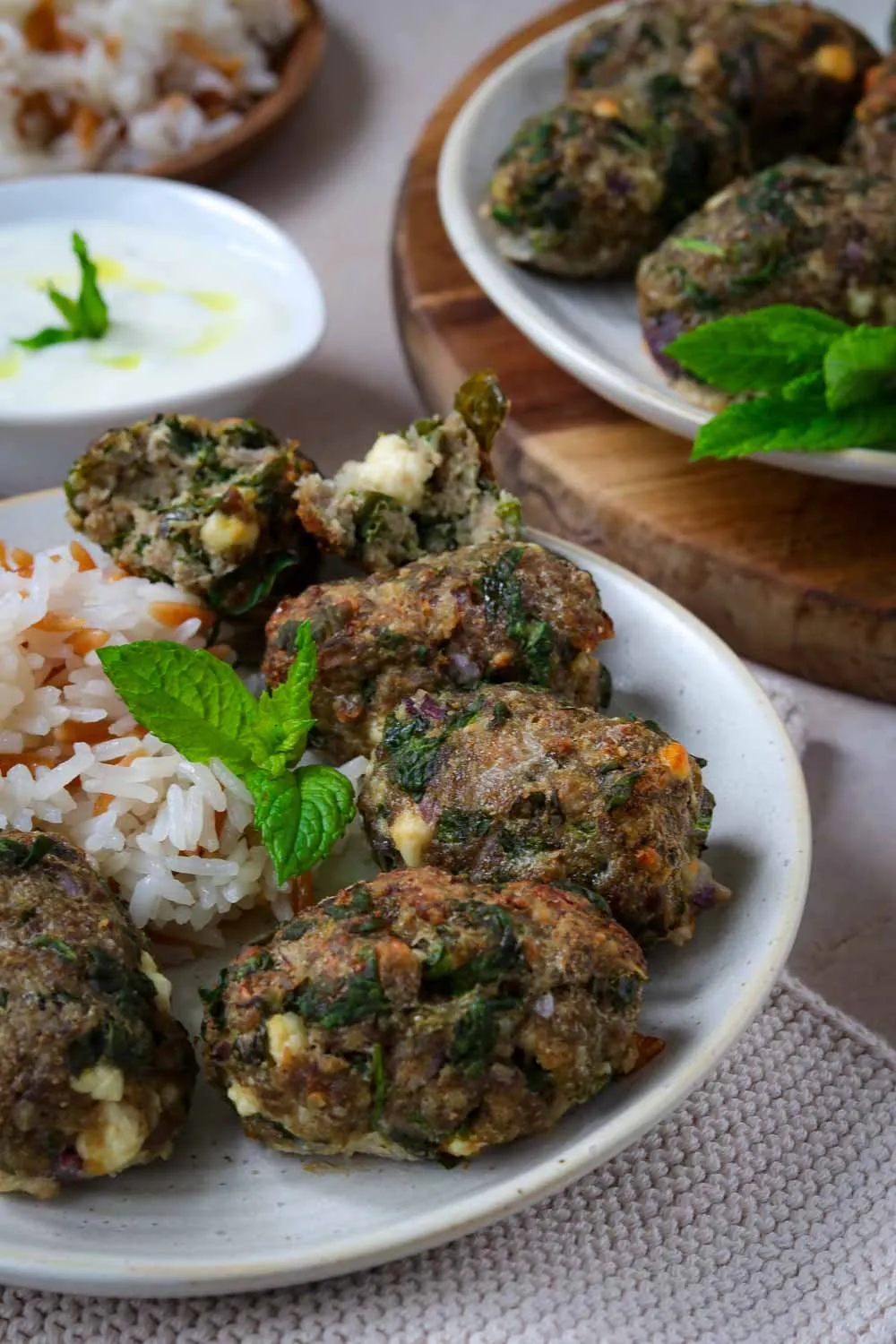 Spinat-Feta-Köfte appetitlich angerichtet mit Dip auf einem Servierbrett