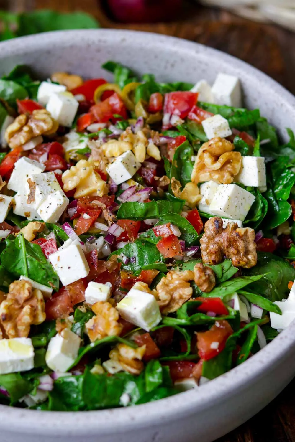 Spinatsalat mit Feta und Walnüssen in einer weißen Schale angerichtet