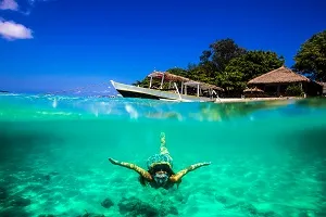 Strand bei Bali, Indonesien, mit Fischerbooten im ruhigen Wasser, perfekt für entspannte Tage im Juli.