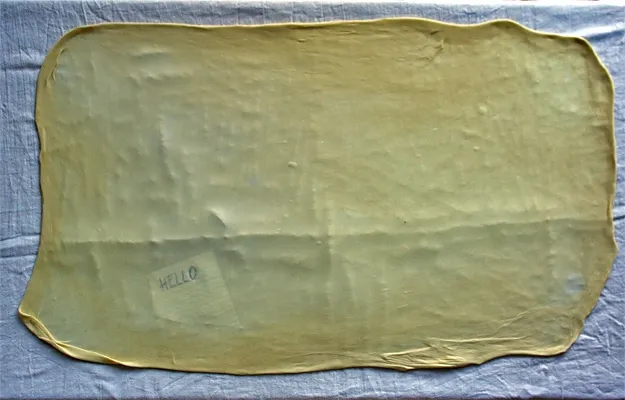 Strudelteig so dünn ausgezogen, dass man darunter liegenden Text lesen kann, essentiell für ein perfektes Strudel Rezept