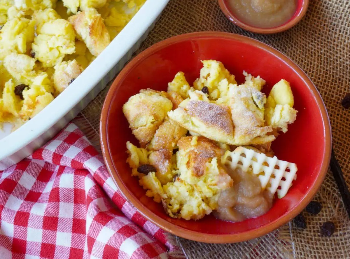 Stück Kaiserschmarrn mit Puderzucker und Apfelmus in einer Auflaufform