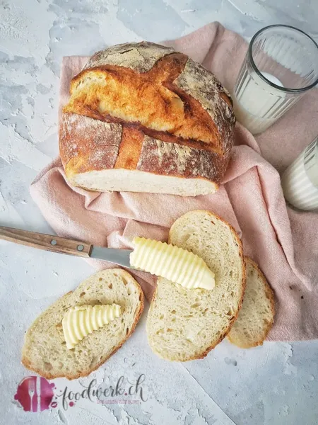 Stück knuspriges Hausbrot bestrichen mit frischer Butter