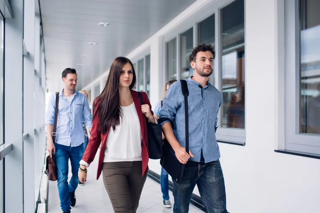Studenten der Universität Klagenfurt auf dem Campus, die zum Hörsaal gehen, im Kontext des Universitätslehrgangs Bildungs- und Berufsberatung.