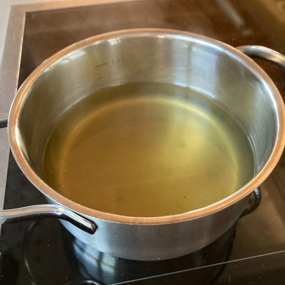 Suppe in einem Topf am Herd. Die klare Brühe köchelt sanft vor sich hin, bereit, die Semmeln aufzunehmen und sich in eine köstliche Sauce zu verwandeln.