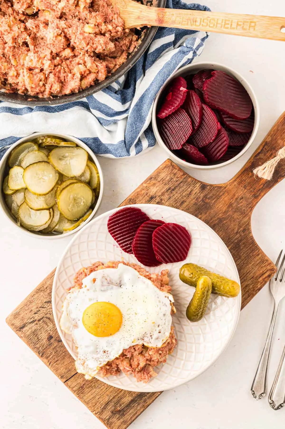 Teller mit Labskaus, Spiegelei und eingelegtem Gemüse wie Rote Bete und Gewürzgurken