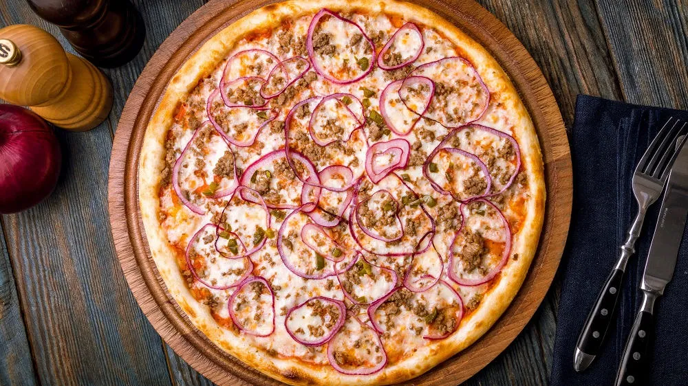 Thunfisch-Pizza appetitlich angerichtet auf einem Holzbrett