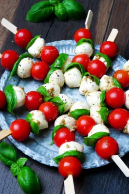 Tomaten-Mozzarella-Spieße als schnelles Fingerfood, dekoriert mit Basilikum