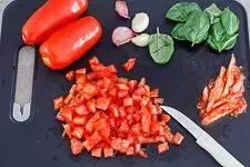 Tomaten und Basilikum werden für den Bruschetta-Belag zerkleinert.