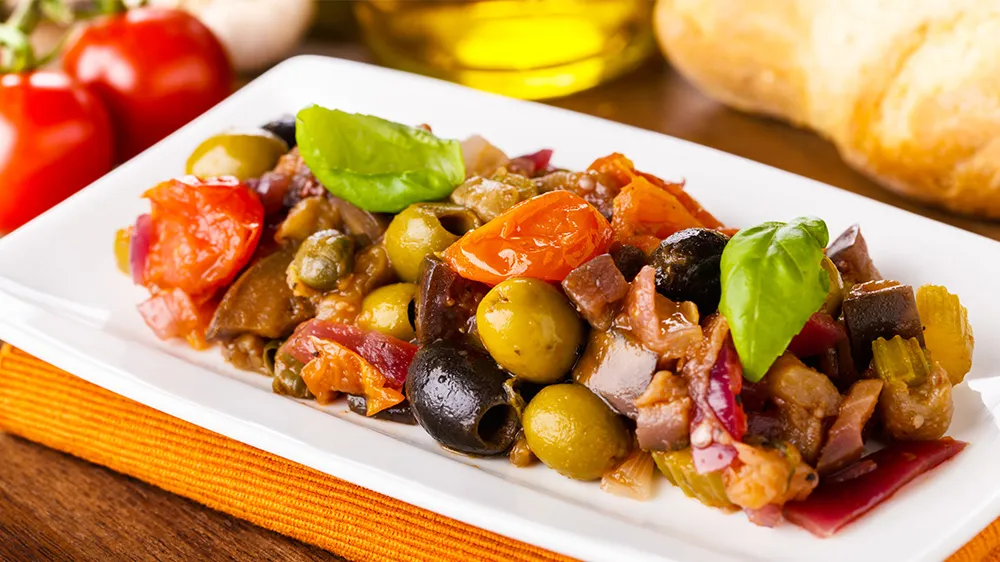 Traditionelle Caponata, ein sizilianischer Auberginen-Eintopf mit Tomaten, Oliven und Kapern, angerichtet in einer rustikalen Schale – ein geschmacksintensives glutenfreies Gericht.