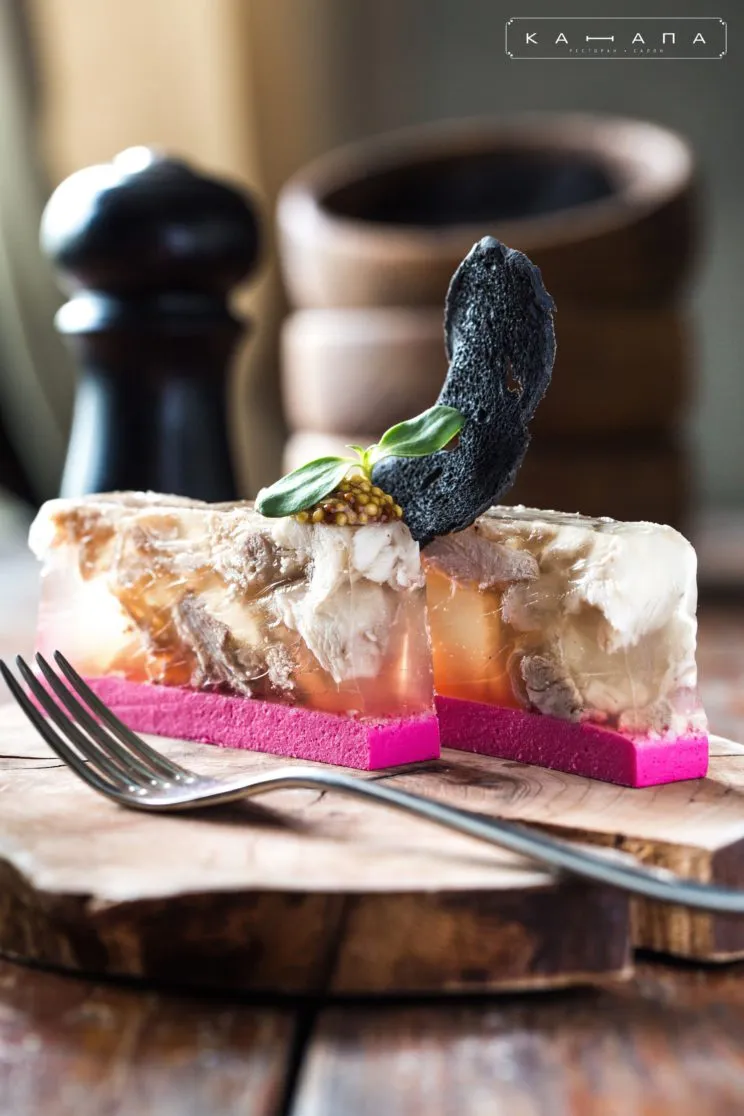 Traditionelles ukrainisches Cholodez, eine herzhafte Sülze mit Fleisch und Gemüse, servierfertig in einer Schale.