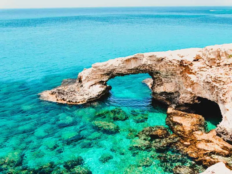 Türkisfarbenes Meer an einer felsigen Küste auf Zypern unter blauem Himmel