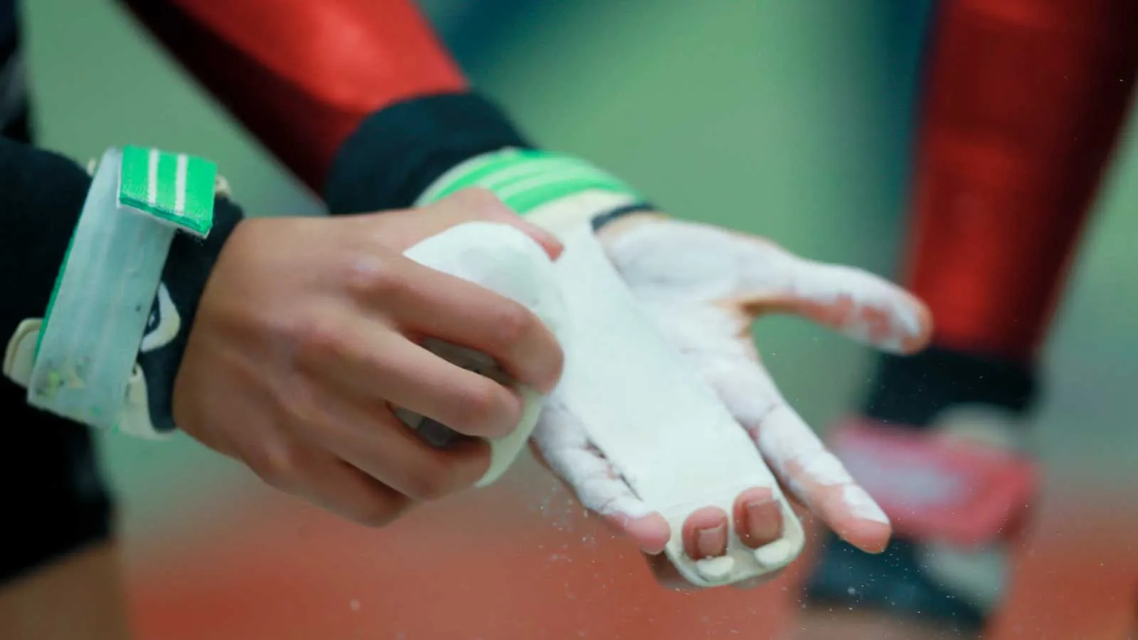 Turnerin beim Kunstturnen, die sich auf den Barren vorbereitet und Hände mit Magnesia pudert