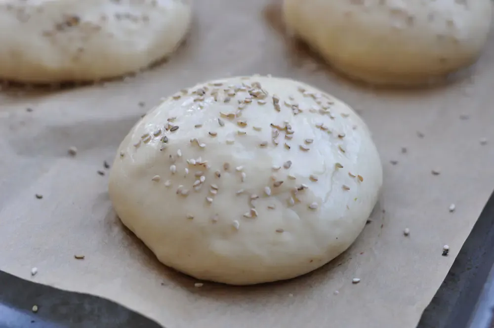 Ungebackener Hamburgerbrötchen-Teigling mit Sesam bestreut