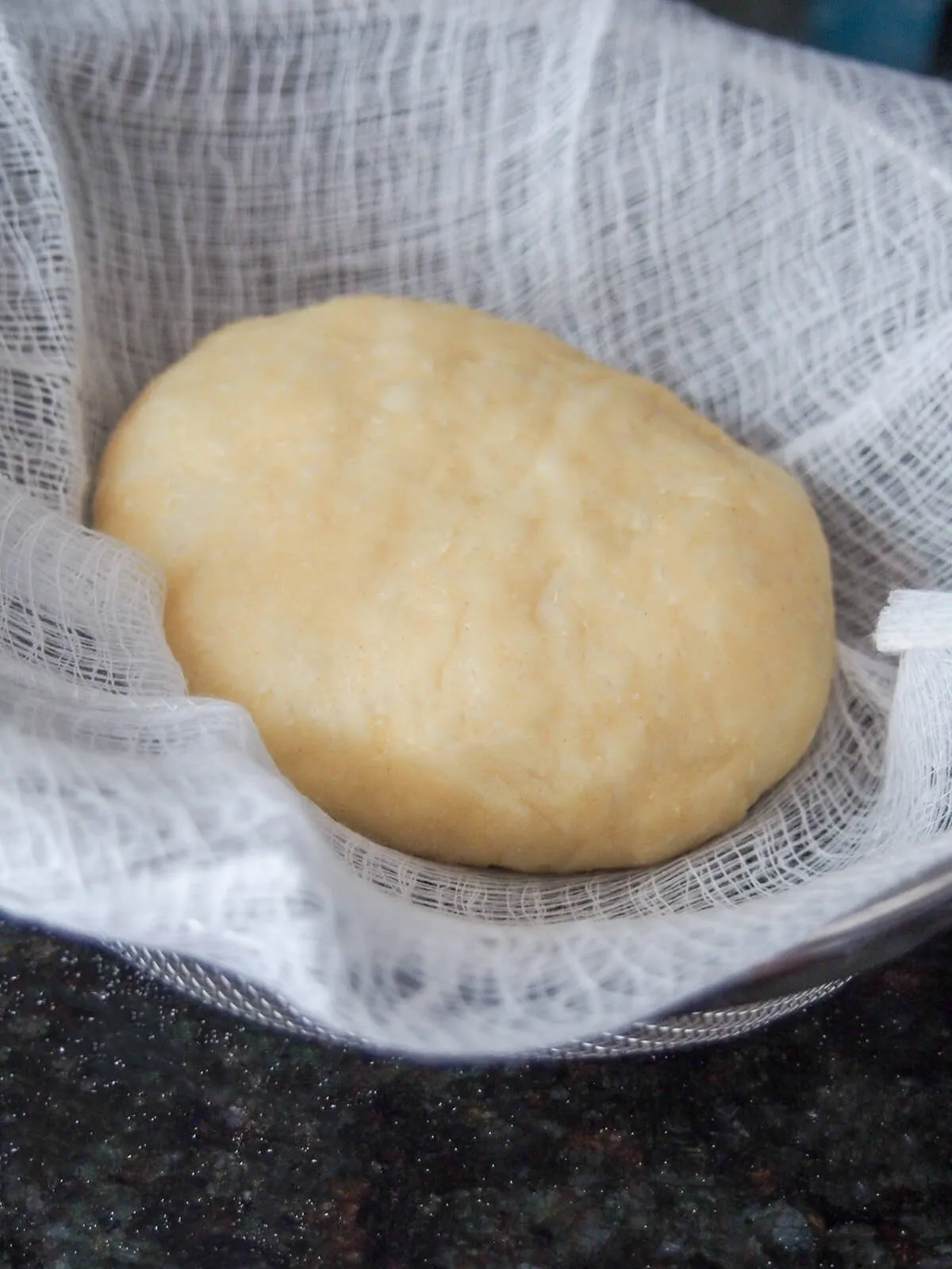 Ungekochter Knödel in einem mit Leinen ausgelegten Sieb, bereit zum Dämpfen.