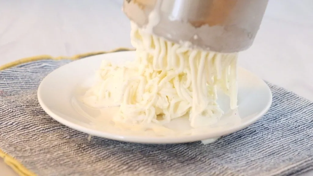 Vanilleeis wird durch eine Kartoffelpresse gedrückt, um Eis-Spaghetti zu formen