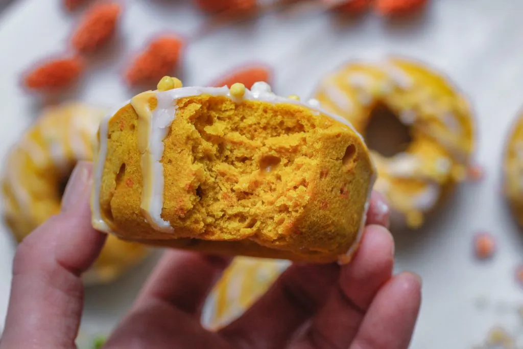 Vegan gebackene Kürbis-Donuts mit Puderzucker und Zitronenglasur auf einem Holzbrett