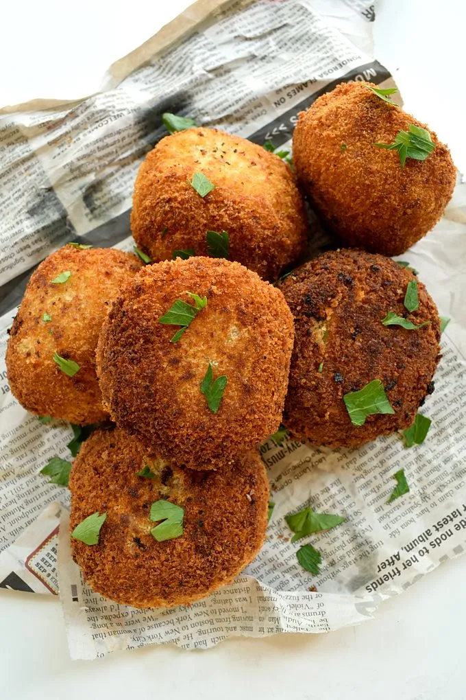 Vegan gefüllte Kartoffelbällchen bereit zum Braten, serviert mit einem pikanten Dip.