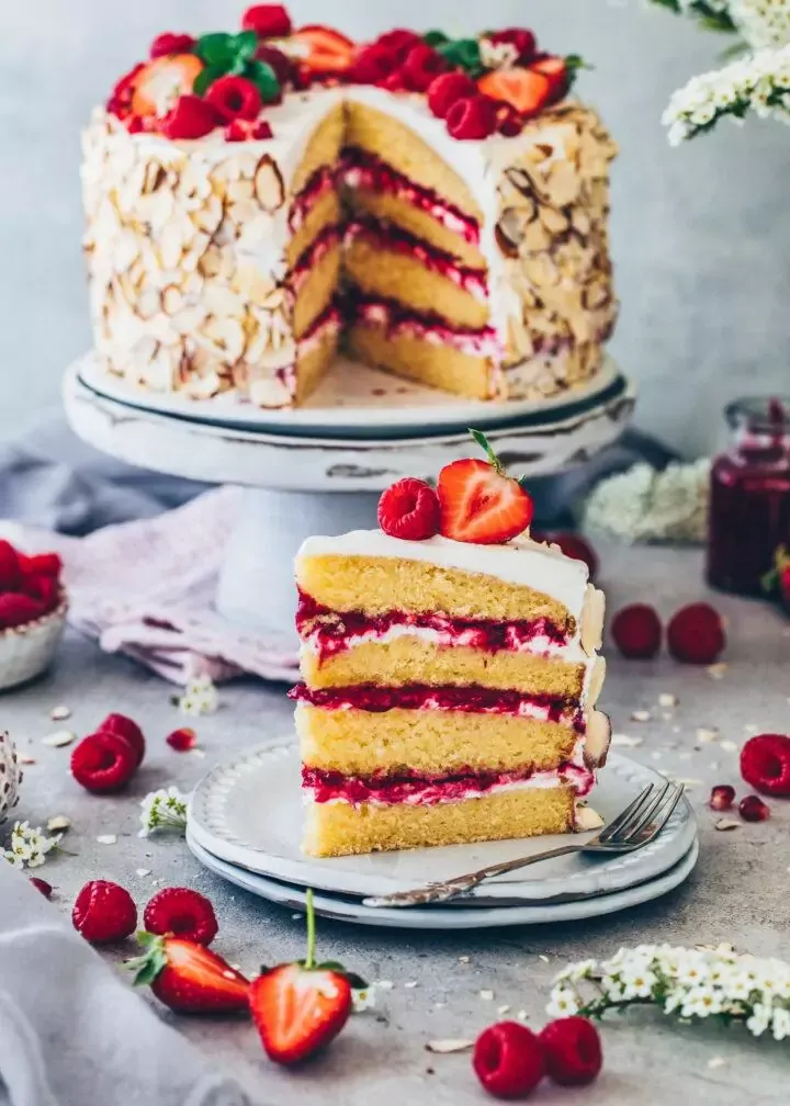 Vegane Himbeer-Sahnetorte mit frischen Himbeeren und Mandeln, perfekt für den Sommer.