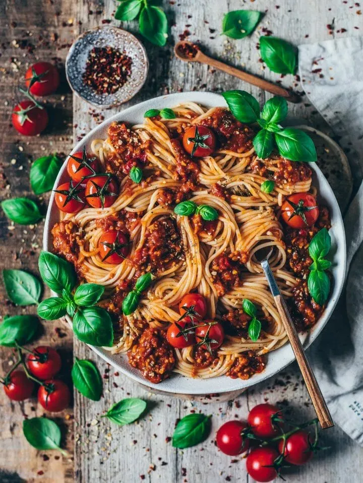 Vegane Spaghetti Bolognese mit frischen Tomaten und Basilikum garniert