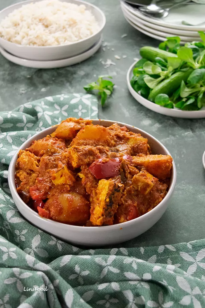 Vegetarisches Curry mit Kartoffeln und Tofu, serviert in einer schwarzen Schale