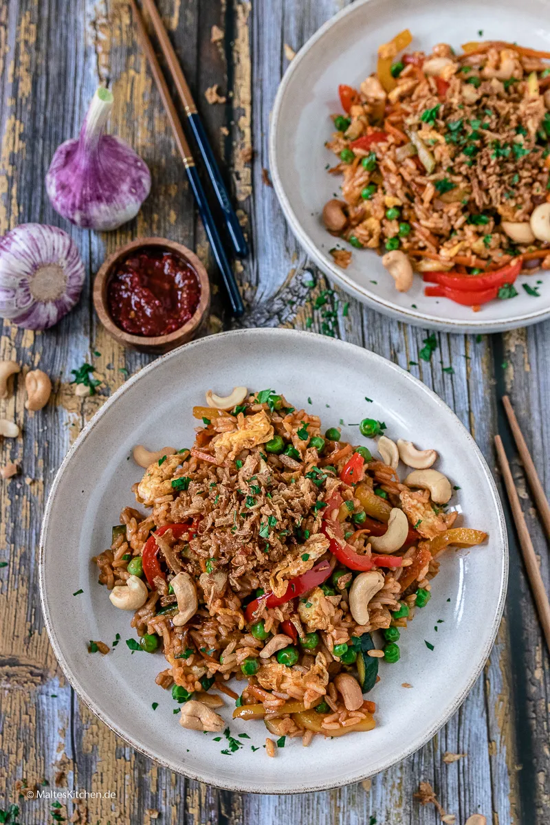 Vegetarisches Nasi Goreng, angerichtet mit frischen Kräutern und Röstzwiebeln