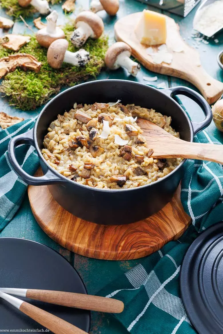 Verschiedene frische Pilze, darunter Champignons, Pfifferlinge und Steinpilze, auf einem Holztisch.