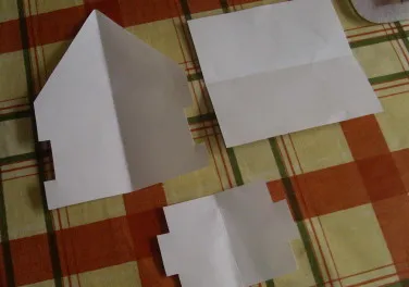 Verschiedene Pappschablonen für die Wände und das Dach eines Lebkuchenhauses, jeweils mit unterschiedlichen Abmessungen.