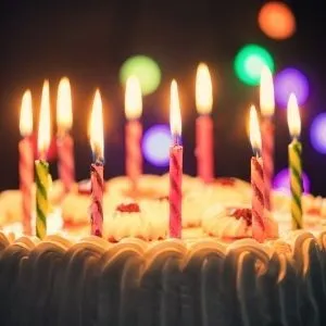 Vielfältige Geburtstagskerzen und Zahlkerzen schmücken eine festliche Torte, symbolisch für deutsche Geburtstagstraditionen.