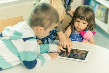 Vier Kinder lernen gemeinsam mit einem Tablet und fördern ihre digitalen Bildungs- und Entwicklungsbereiche