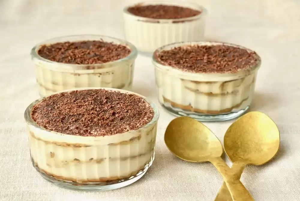 Vier Schälchen mit hausgemachtem veganen Tiramisu, bereit zum Servieren.