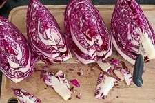 Viertel eines Rotkohlkopfes auf einem Schneidebrett, bereit zum Entfernen des Strunks und Zerkleinern für das Rotkraut Rezept.