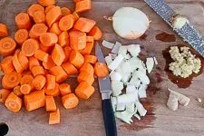 Vorbereitete, grob gewürfelte Karotten und Zwiebeln sowie geriebener Bio-Ingwer als erster Schritt der Karotten Ingwer Suppen Zubereitung.