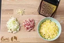 Vorbereitete Zutaten: Fein gewürfelte Zwiebel, Knoblauch, Speck und geriebener Käse