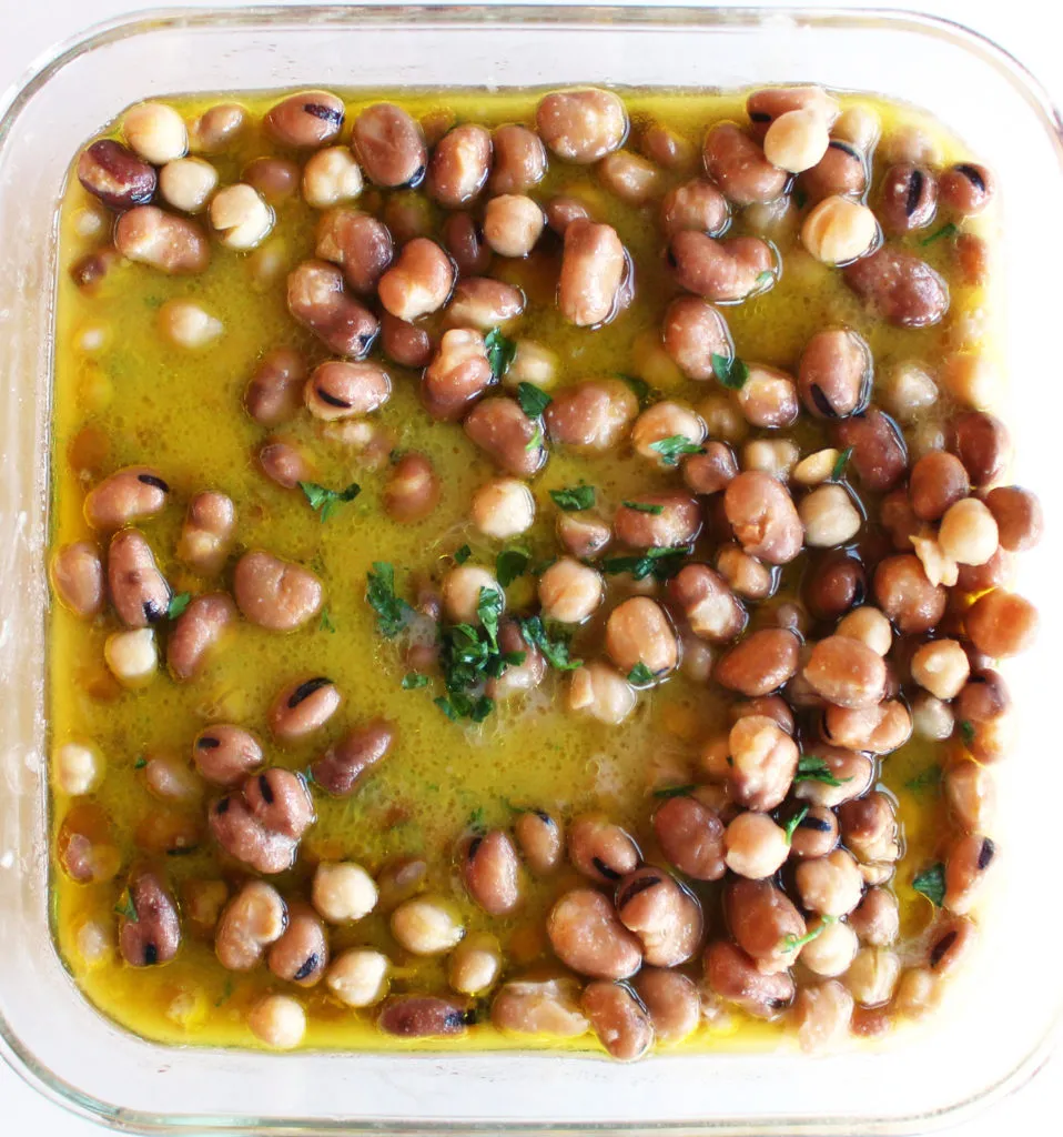 Vorbereitete Zutaten für Ful Medames, inklusive gekochter Favabohnen und Kichererbsen in einer Pfanne, bereit für die Zubereitung des syrischen Bohnensalats.